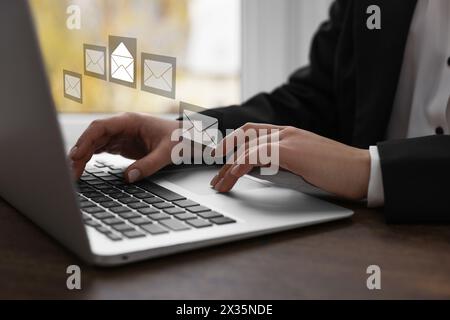 Email. Woman using laptop at table, closeup. Letter illustrations over device Stock Photo