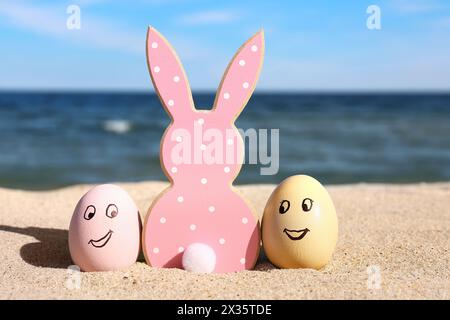 Cookie in shape of bunny and painted Easter eggs on sea beach Stock Photo