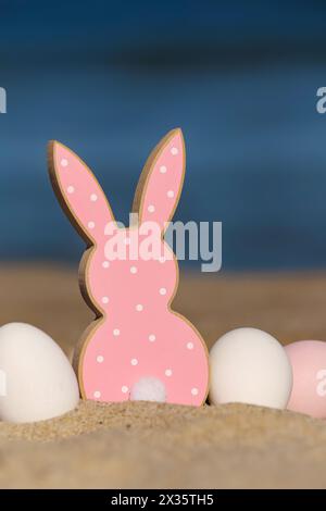 Painted Easter eggs and cookie in shape of bunny on sea beach Stock Photo
