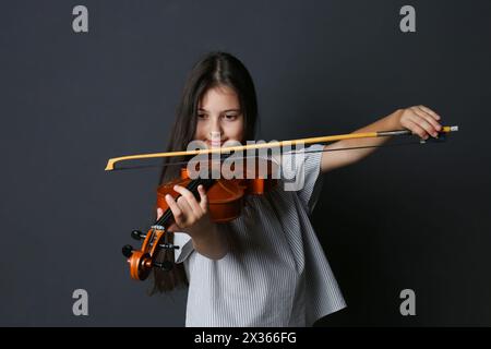 Preteen girl playing violin on black background Stock Photo - Alamy