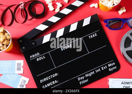 Flat lay composition with clapperboard and popcorn on red background Stock Photo