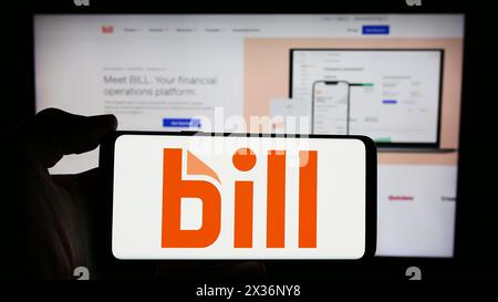 Person holding cellphone with logo of US financial software company BILL Holdings Inc. in front of business webpage. Focus on phone display. Stock Photo