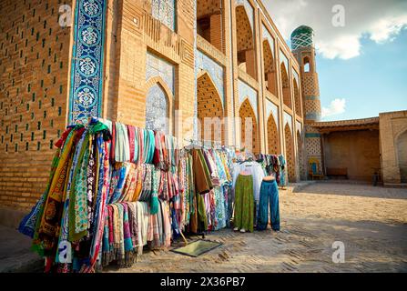 Ethnic colorful cloth and scarf with traditional uzbekistan ornament on street market near old madrasah in Khiva, Uzbekistan, Central Asia. Stock Photo