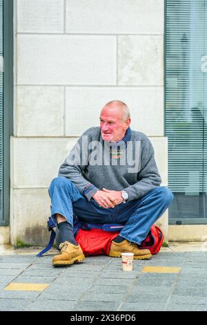 Middle-aged man sitting on city street corner begging for money - Tours, Indre-et-Loire (37), France. Stock Photo