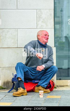 Middle-aged man sitting on city street corner begging for money - Tours, Indre-et-Loire (37), France. Stock Photo