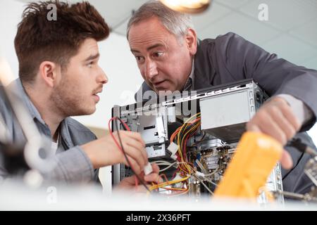 happy electronic engineers examining digital multimeter indicators Stock Photo