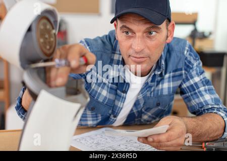 adult handyman repairing coffee machine with screwdriver in workshop Stock Photo