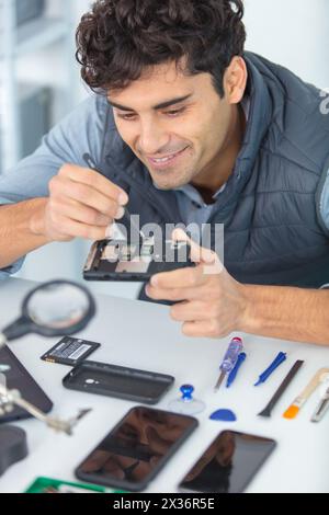 young repairman separating mobile phone parts for diagnostics Stock Photo