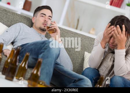 battered woman and drunk man on sofa at home Stock Photo