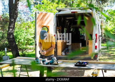 Man sanding wood to camperize a camper van Stock Photo