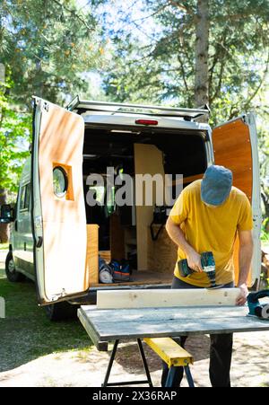 Man preparing a piece of wood to customize a camper van Stock Photo
