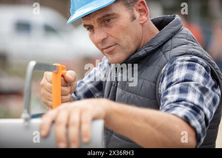 plumbing sawing plastic pipe on construction site Stock Photo