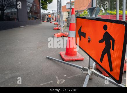 Man Walking Road sign along a closed footpath. Unrecognizable workers in the distance. Roadworks in Auckland. Stock Photo