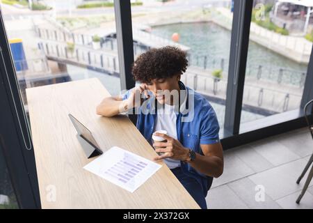 A young biracial man wearing headphones, examining graphs on tablet Stock Photo