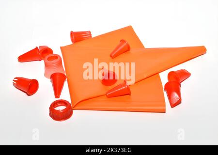 Various shapes of nozzles for a pastry syringe and a fabric syringe lie on a white background. Stock Photo