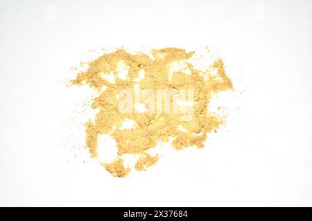 Ground ginger spice is scattered on a white background and is used in cooking. Stock Photo