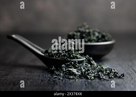 Dried wakame seaweed in spoon on a black table. Stock Photo