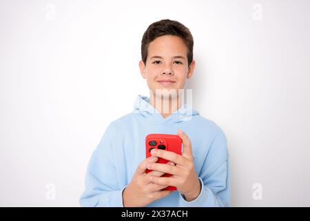 Portrait of boy using smartphone texting, standing isolated on white background. Stock Photo