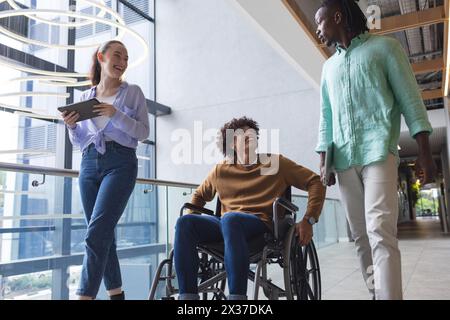 Diverse colleagues walking and talking in bright hallway in a modern business office Stock Photo
