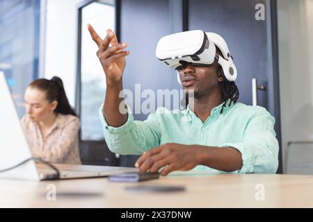African American man wearing VR headset and pointing in modern business office Stock Photo