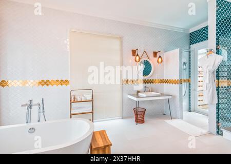 Beautiful luxury bathroom with a blue vanity cabinet, standalone bathtub and shower, and gold faucets and decorations. Elegant home interior Stock Photo