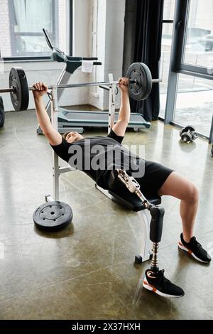 A man, with a prosthetic leg, is performing a bench press exercise with a barbell at the gym. Stock Photo