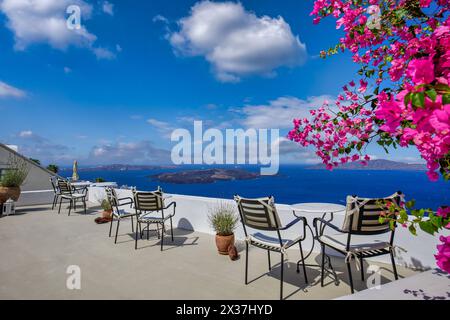Romantic couple outdoor white marble tables chairs on terrace with flowers overlooking sea, Oia Village, Santorini, Cyclades, Greece. Summer holiday, Stock Photo
