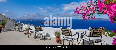 Romantic couple outdoor white marble tables chairs on terrace with flowers overlooking sea, Oia Village, Santorini, Cyclades, Greece. Summer holiday, Stock Photo