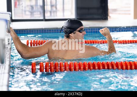 Caucasian young male swimmer with dark hair is training indoors in a pool Stock Photo