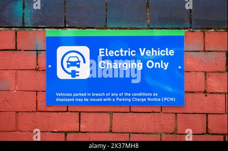 A blue and green sign indicating a parking spot is reserved for electric vehicle charging only, London, UK. Stock Photo