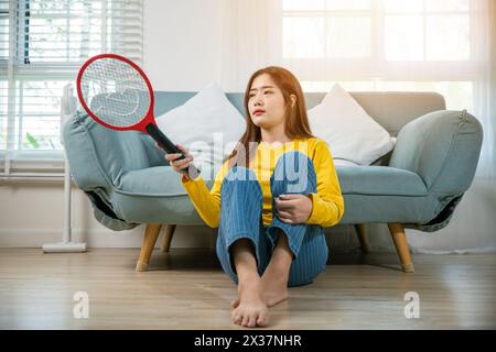 Woman killing mosquitoes hand holding fly swatter like weapon Stock Photo