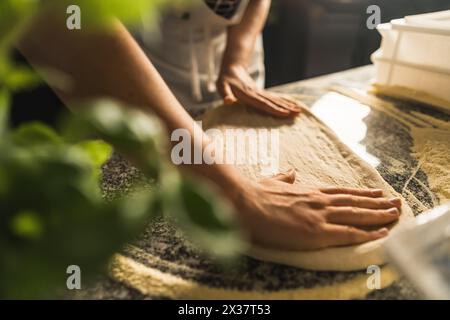 hands stretching pizza dough on floured surface. Expert touch in traditional Italian pizza making art. High quality photo Stock Photo