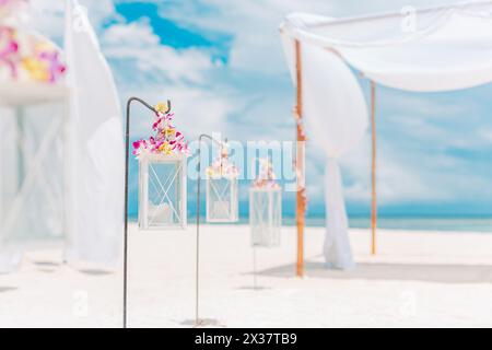 Romantic wedding ceremony on the beach, white decoration, candles flowers on white sand with blue sky. Luxury summer beach wedding wedding anniversary Stock Photo