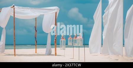 Romantic wedding ceremony on the beach, white decoration, candles flowers on white sand with blue sky. Luxury summer beach wedding wedding anniversary Stock Photo