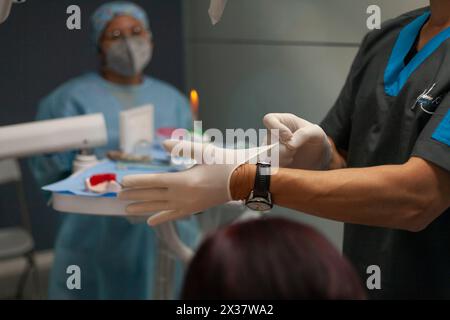Dentist putting on latex gloves Stock Photo