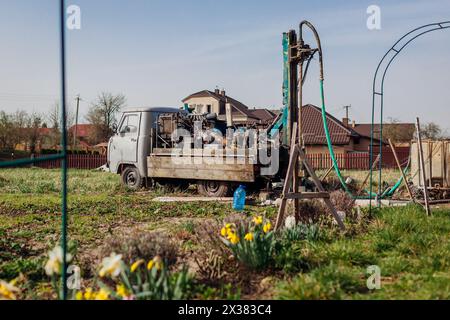 Drilling machine digging water hole in ground for well installation. Geology rig work equipment assembled on old truck Stock Photo