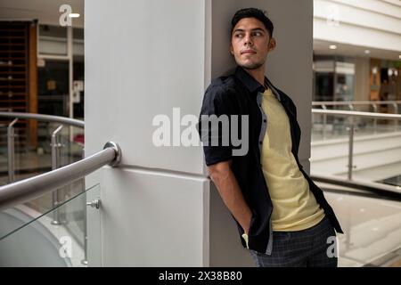 Portrait of Young Latin American Man with relaxed attitude standing and leaning against a wall. Stock Photo