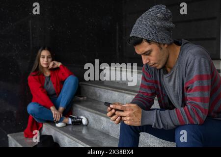 Two young Latin American brothers hanging out sitting on the stairs. Selective approach. Technology and brotherhood concept Stock Photo