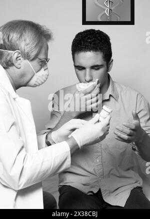 GP in mask gives prescription to coughing teen patient. Stock Photo