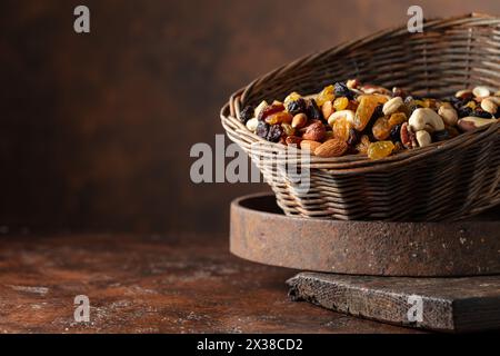 Mix of various nuts and raisins in a old basket on a brown background. Copy space. Stock Photo