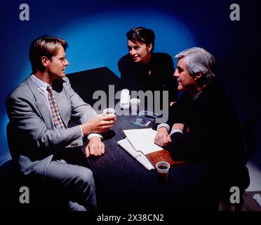Business & Professions. Young woman & two men seated at a table. Stock Photo
