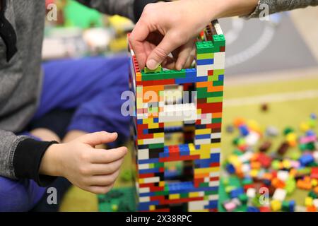 Hands of mother and son playing with colored erector set on floor in room Stock Photo