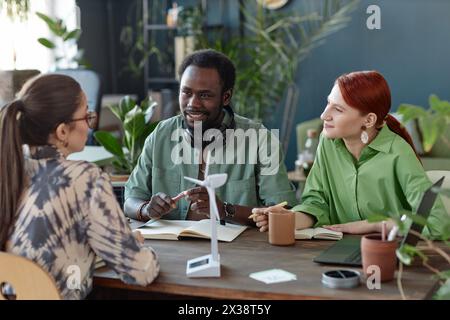 Multiethnic team of creative business people discussing ideas at meeting table in green office Stock Photo