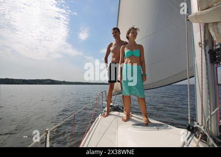 Man and woman stands on snout of white yacht on river at summer sunny day Stock Photo