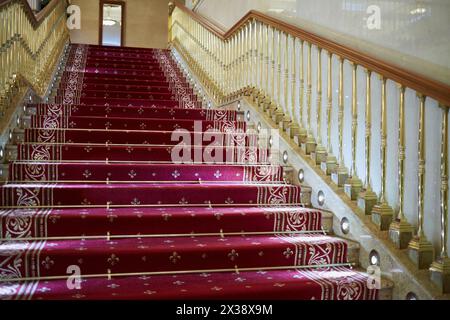 Stairs with handrails covered with red carpet. Stock Photo