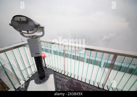Binoculars on viewing platform on snowy day and buildings in fog in Moscow Stock Photo