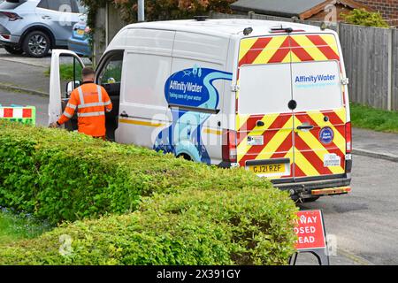 Affinity Water engineer at work on customers water supply in  front garden parked up in residential street side back view of van in Essex England UK Stock Photo