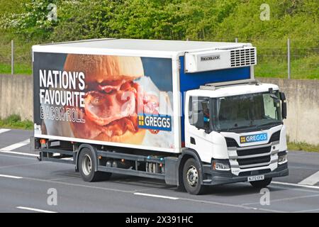 Bacon Roll Nations Favorite adver on side of Greggs bakery chain business on rigid body delivery lorry truck driving on M25 motorway Essex England UK Stock Photo