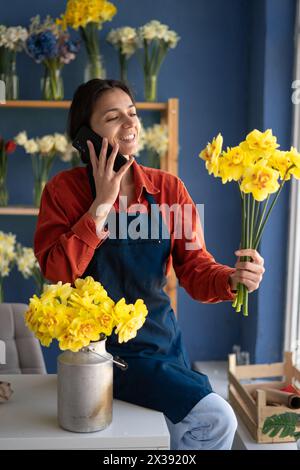 Hispanic woman florist working from home, taking order from client to arrange flower bouquet, delivery. Stock Photo