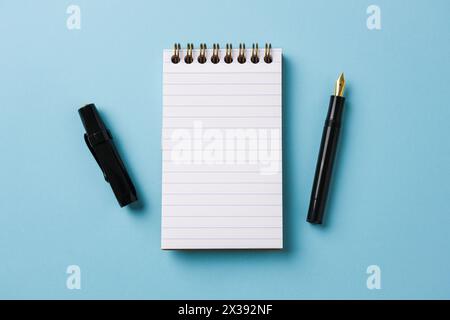 Top view of notebook and fountain pen on blue background Stock Photo